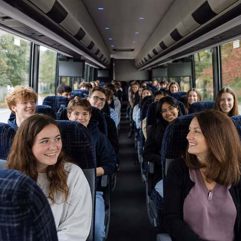Group boarding a white charter bus for School Transportation transportation in Little Rock