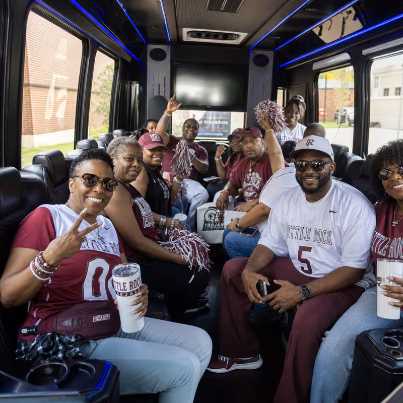 Group boarding a white charter bus for Sporting Event Transportation transportation in Little Rock